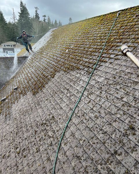 a man is cleaning a roof with a pressure washer .