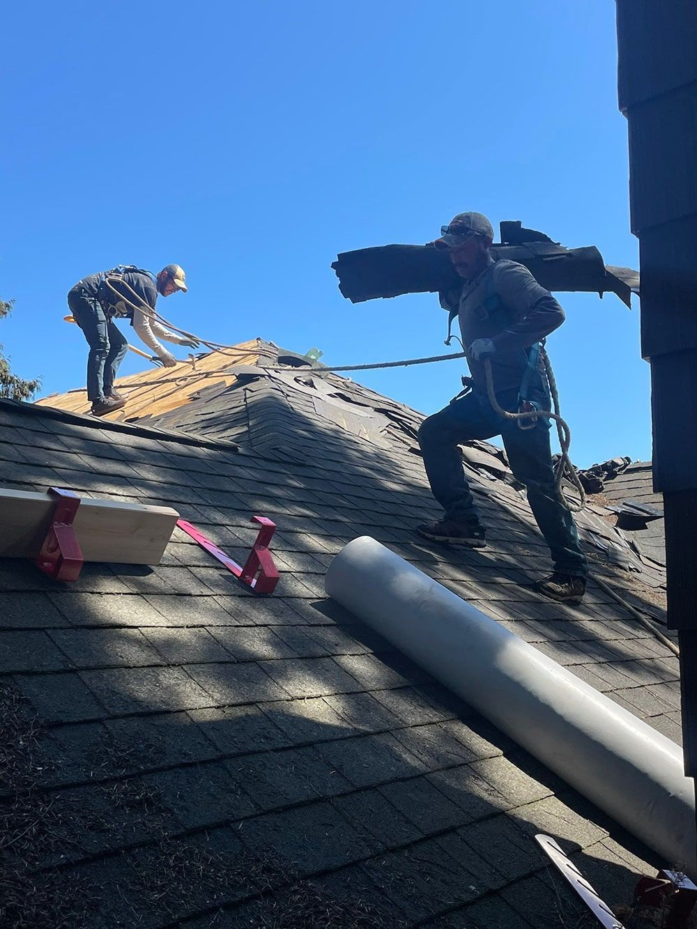 two men are working on the roof of a house .