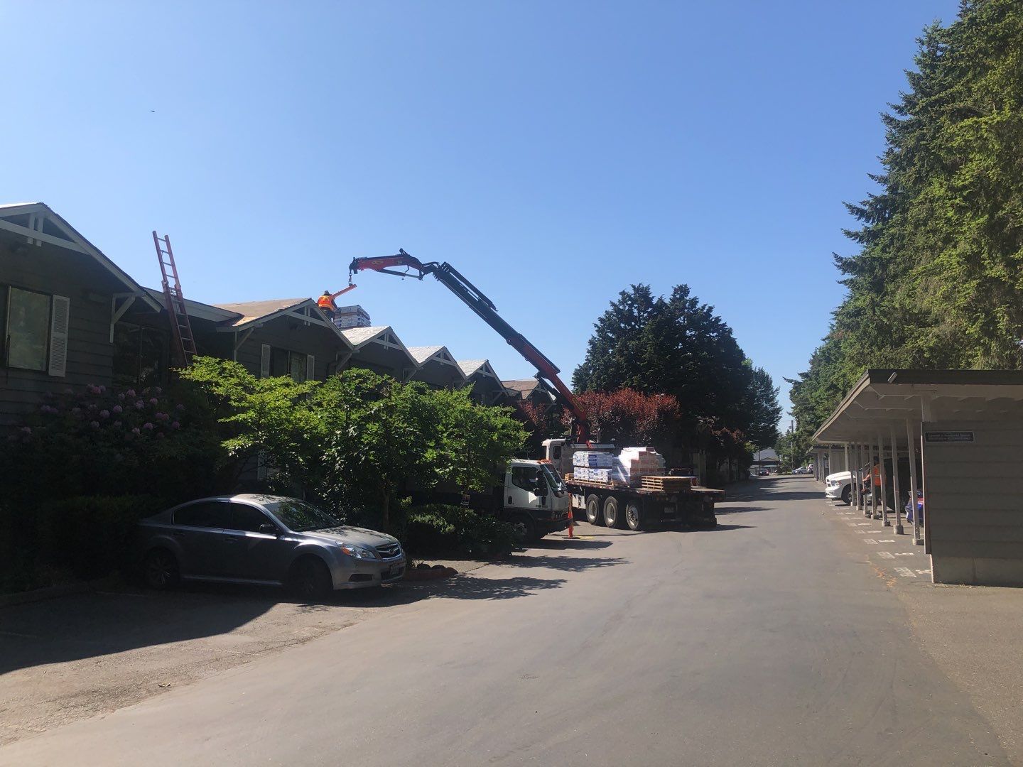 a crane is working on a roof of a building in a residential area .