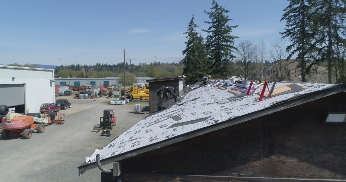 a roof is being installed on a building in a parking lot .