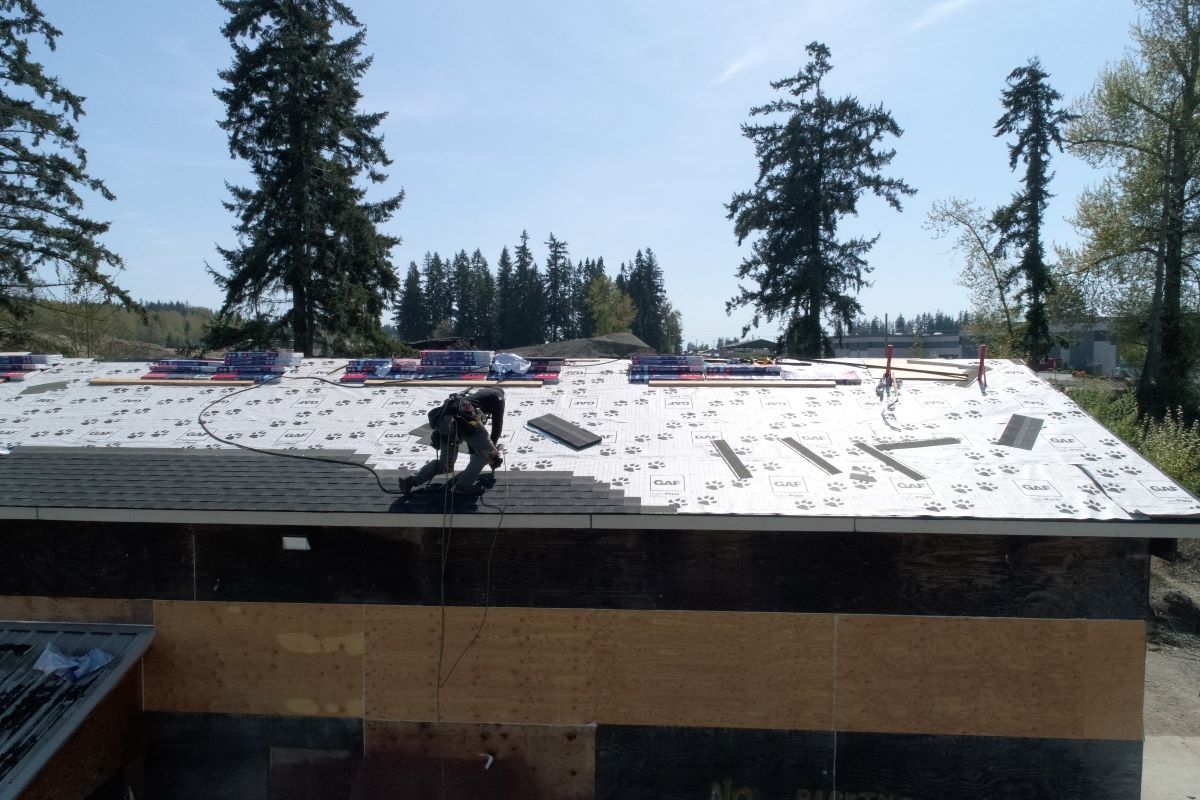 a man is working on a roof with trees in the background
