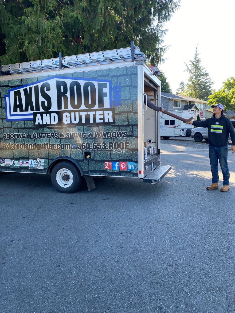 a man is standing in front of a truck that says axis roof and gutter .