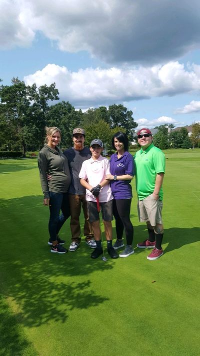 a group of people are posing for a picture on a golf course .