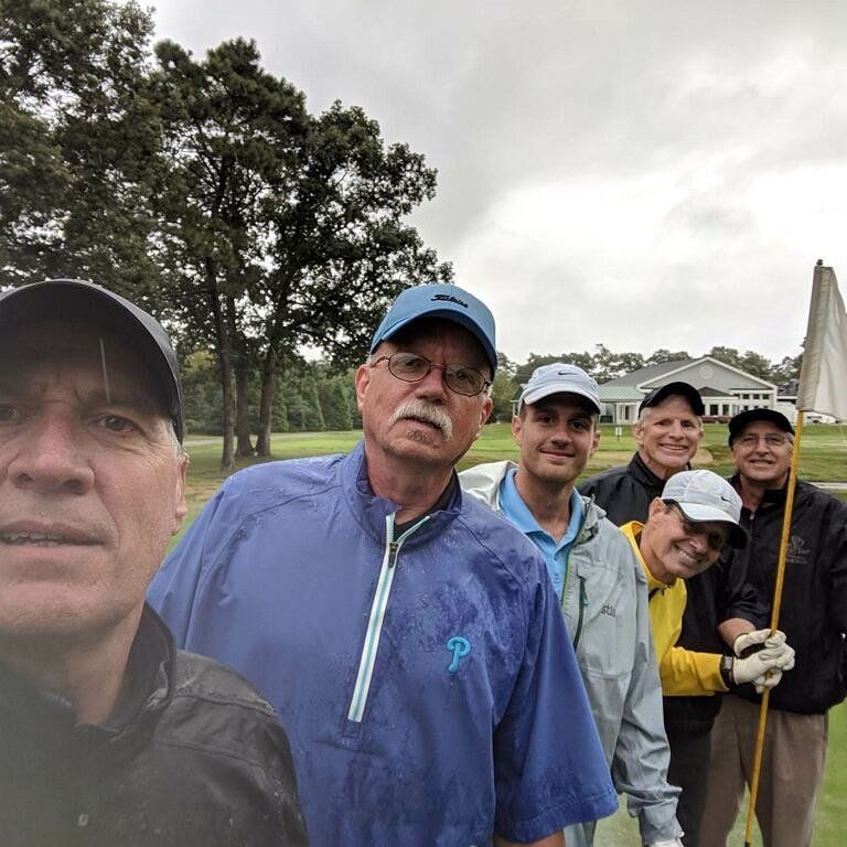a group of men are posing for a picture on a golf course