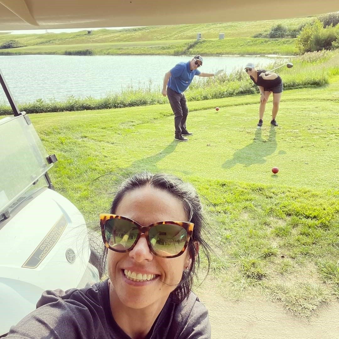 a woman wearing sunglasses is smiling in front of a golf cart