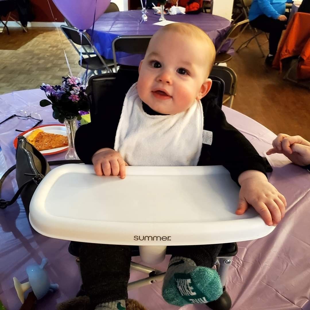 a baby wearing a bib is sitting in a high chair