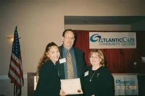 a man and two women are standing next to each other holding a certificate .