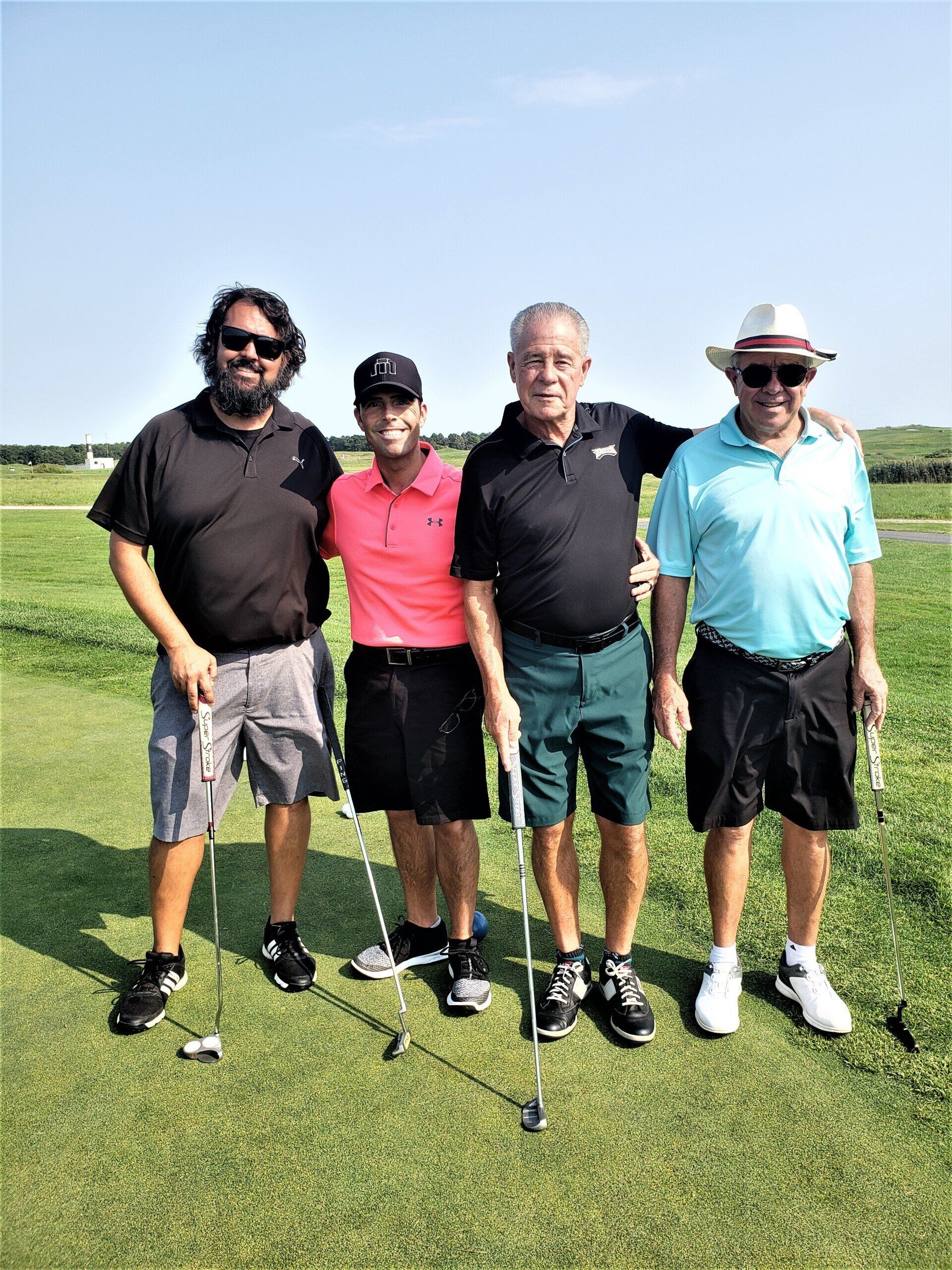 four men are posing for a picture on a golf course