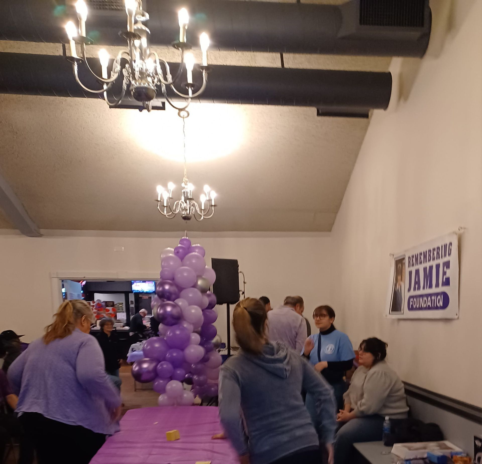 a group of people gathered around a table with purple balloons