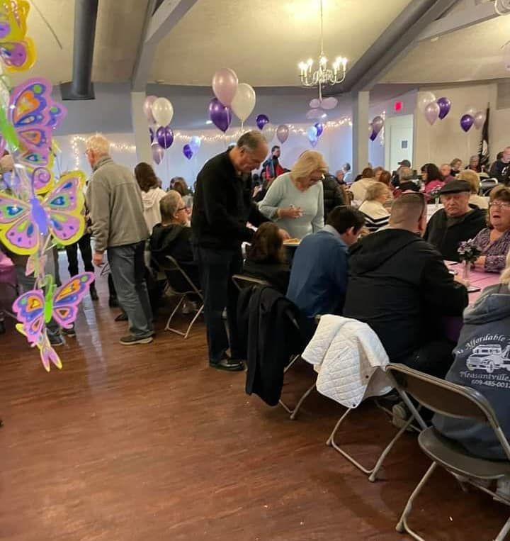a group of people sitting at tables with balloons hanging from the ceiling