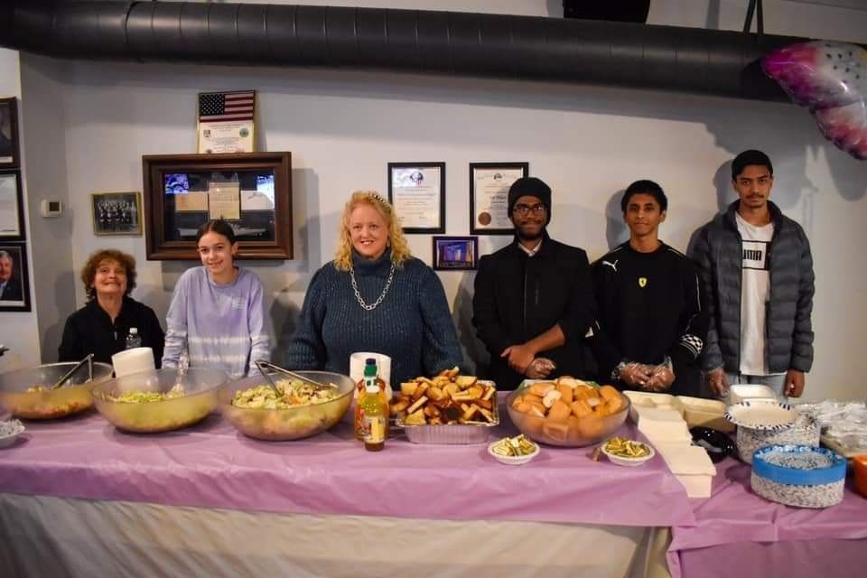 a group of people are standing around a table with food on it .