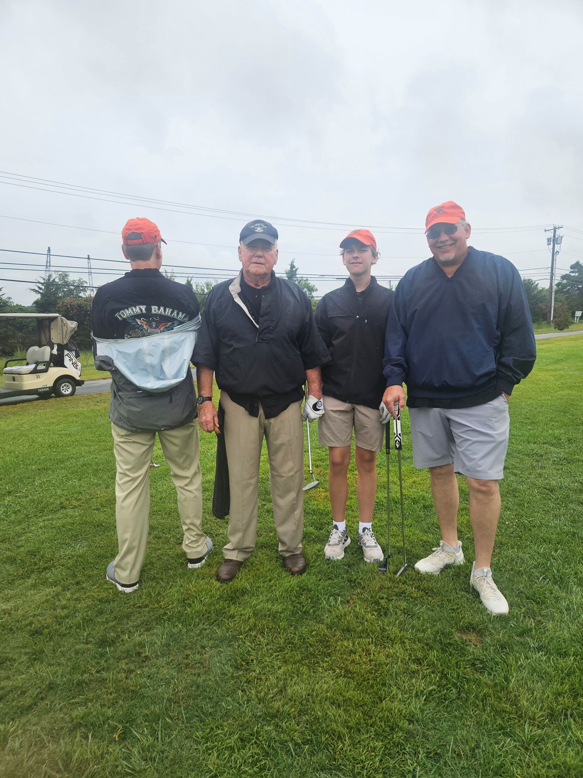 Four men on the golf course at McCullough's Emerald Links Golf Course in Egg Harbor Township, New Jersey during the 2025 Remembering Jamie Golf Tournament, wearing caps and casual clothing on a cloudy day