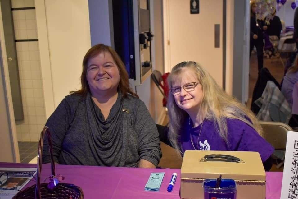 two women are sitting at a table and smiling for the camera