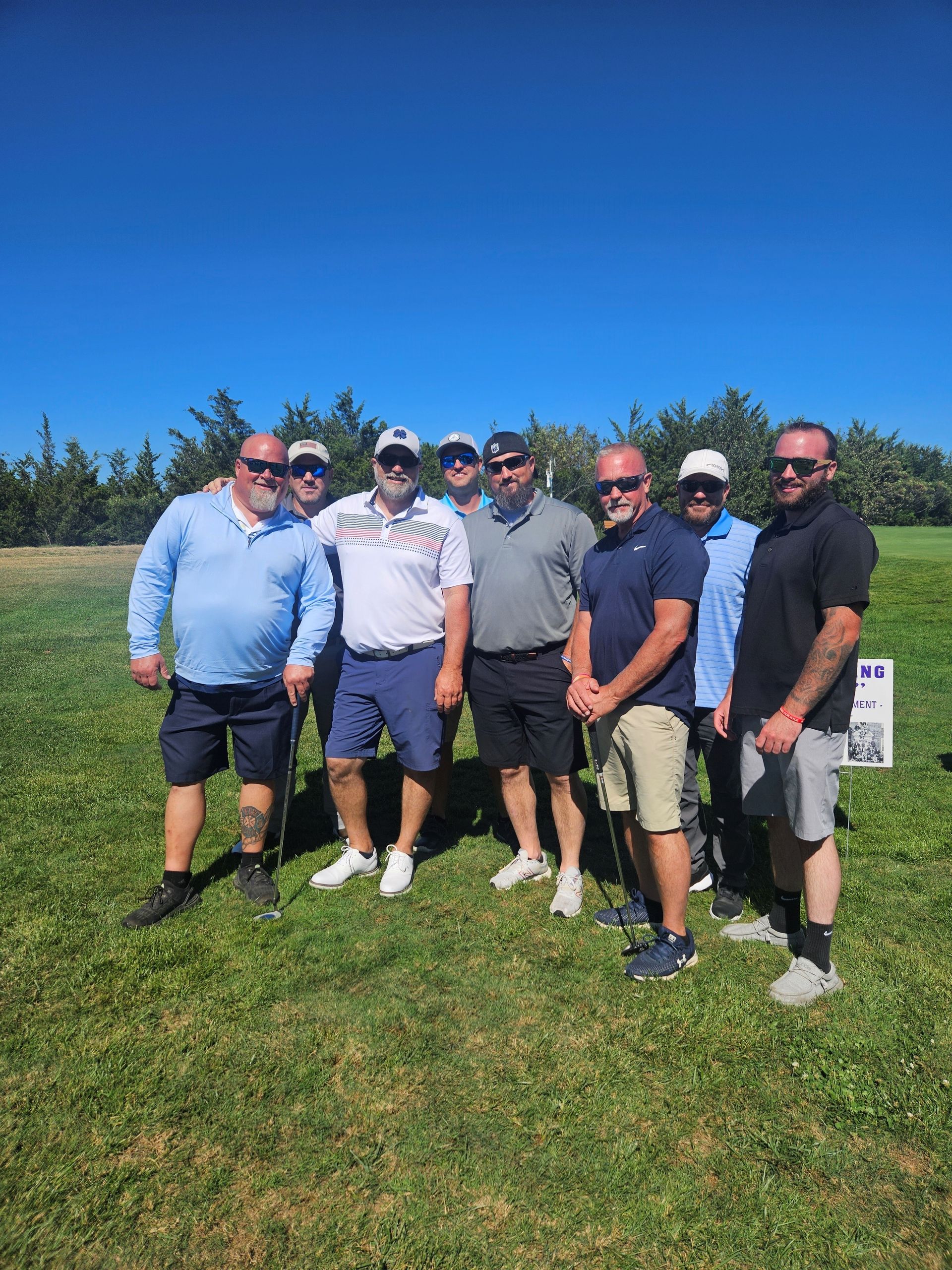 A group of men are posing for a picture on a golf course for the remembering jamie golf tournament