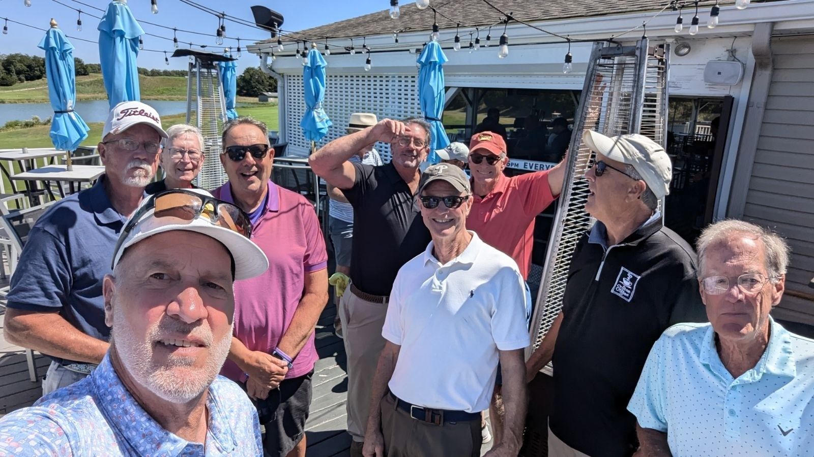 A group of men are posing for a picture on the back deck of mccullough's emerald links golf course for the remembering jamie golf tournament