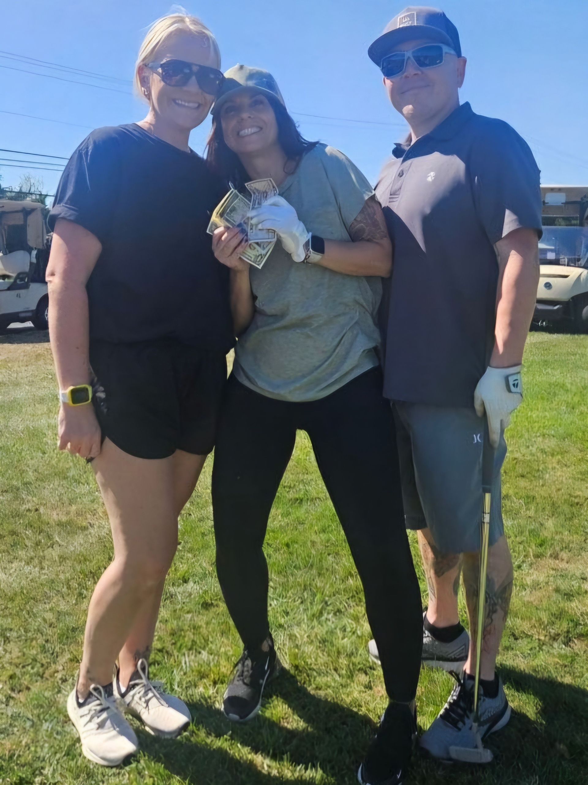 Three people are posing for a picture on a golf course