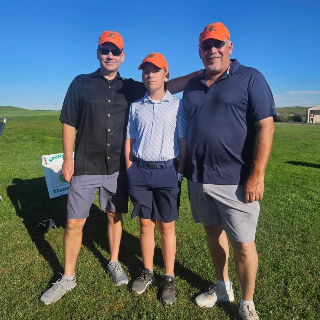 Three men are posing for a picture on a tee box at golf course