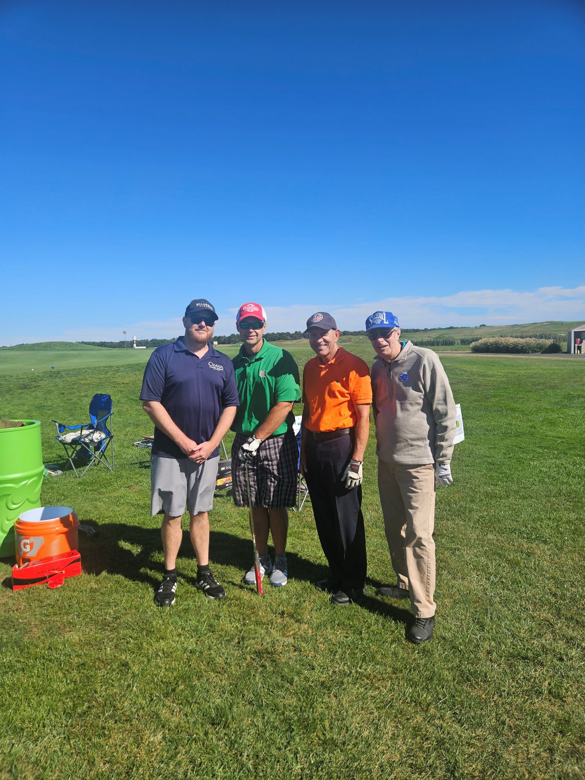 A group of men are standing in a grassy field for the remembering jamie golf tournament