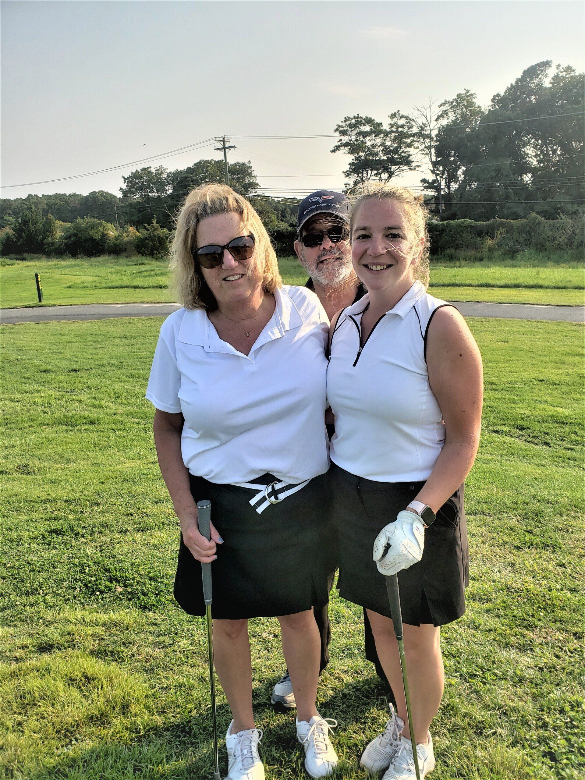 three women are posing for a picture on a golf course