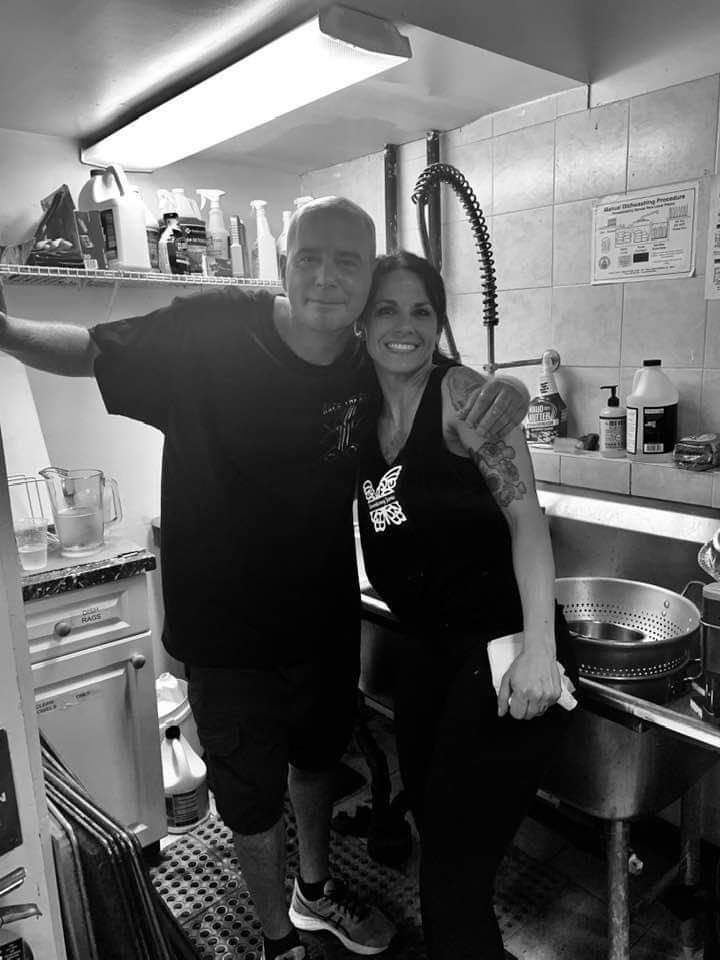 a man and a woman are posing for a picture in a kitchen .
