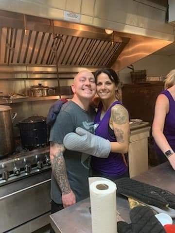 a man and a woman are hugging in a kitchen .