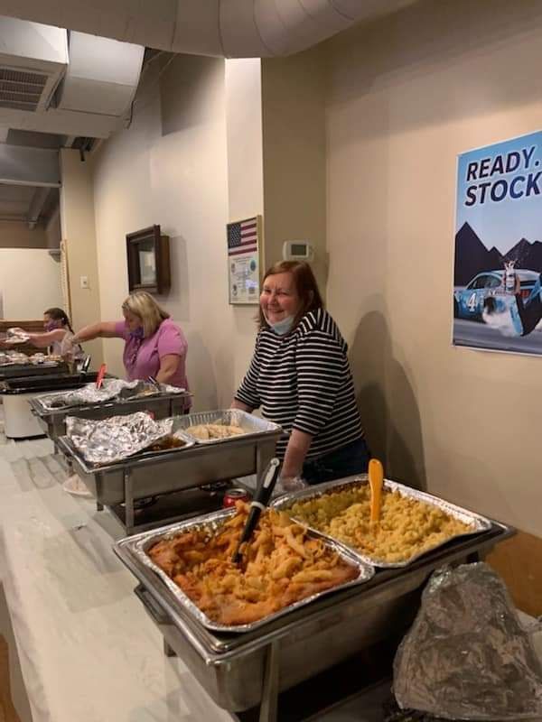 a woman is standing behind a buffet line filled with food .