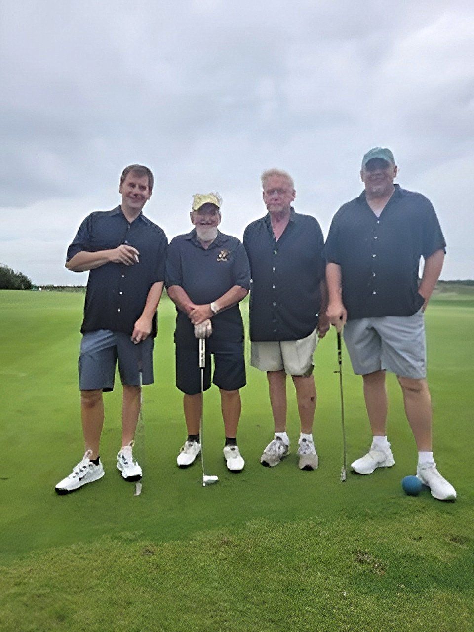 a group of men are standing on a golf course holding golf clubs .