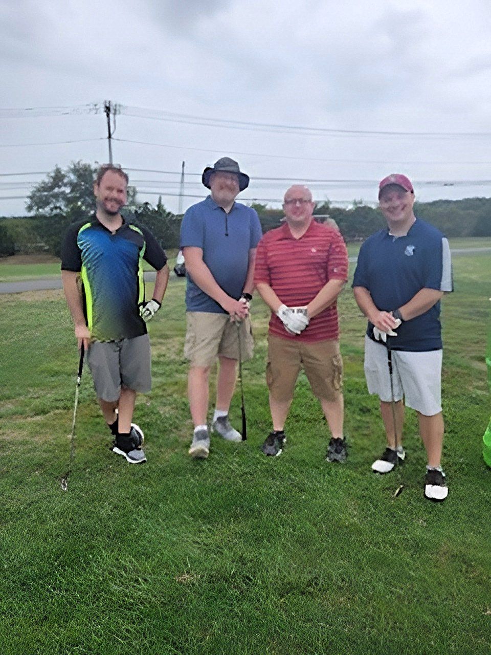 a group of men are standing on a golf course holding golf clubs .