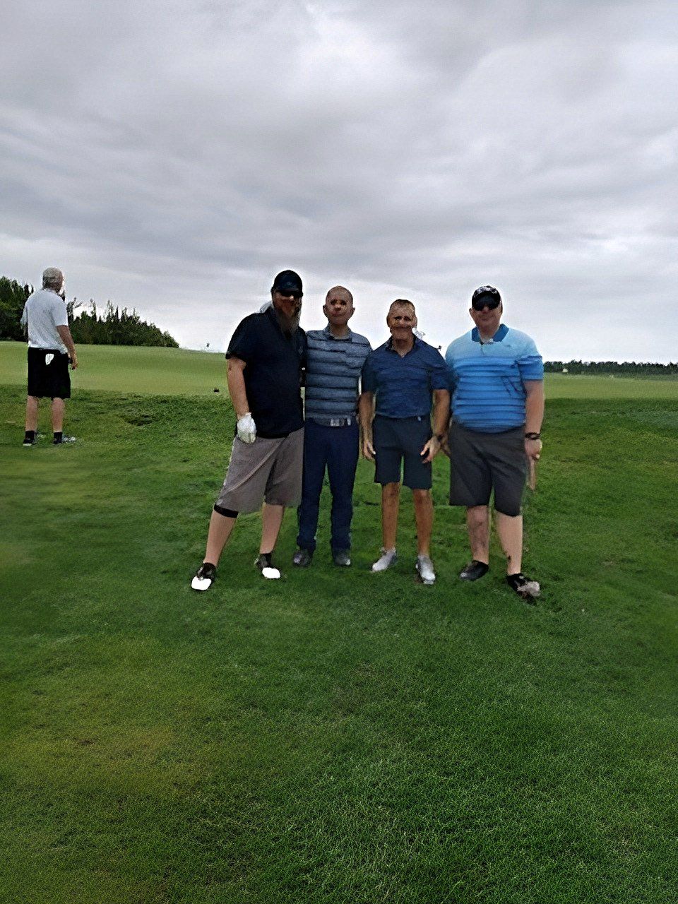 a group of men are posing for a picture on a golf course .