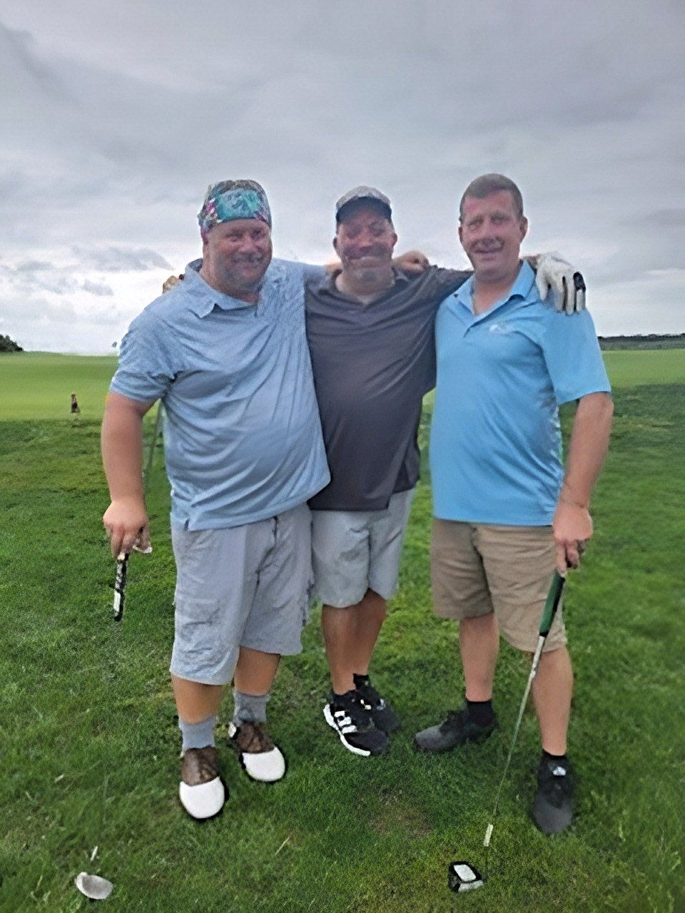 three men are posing for a picture on a golf course .