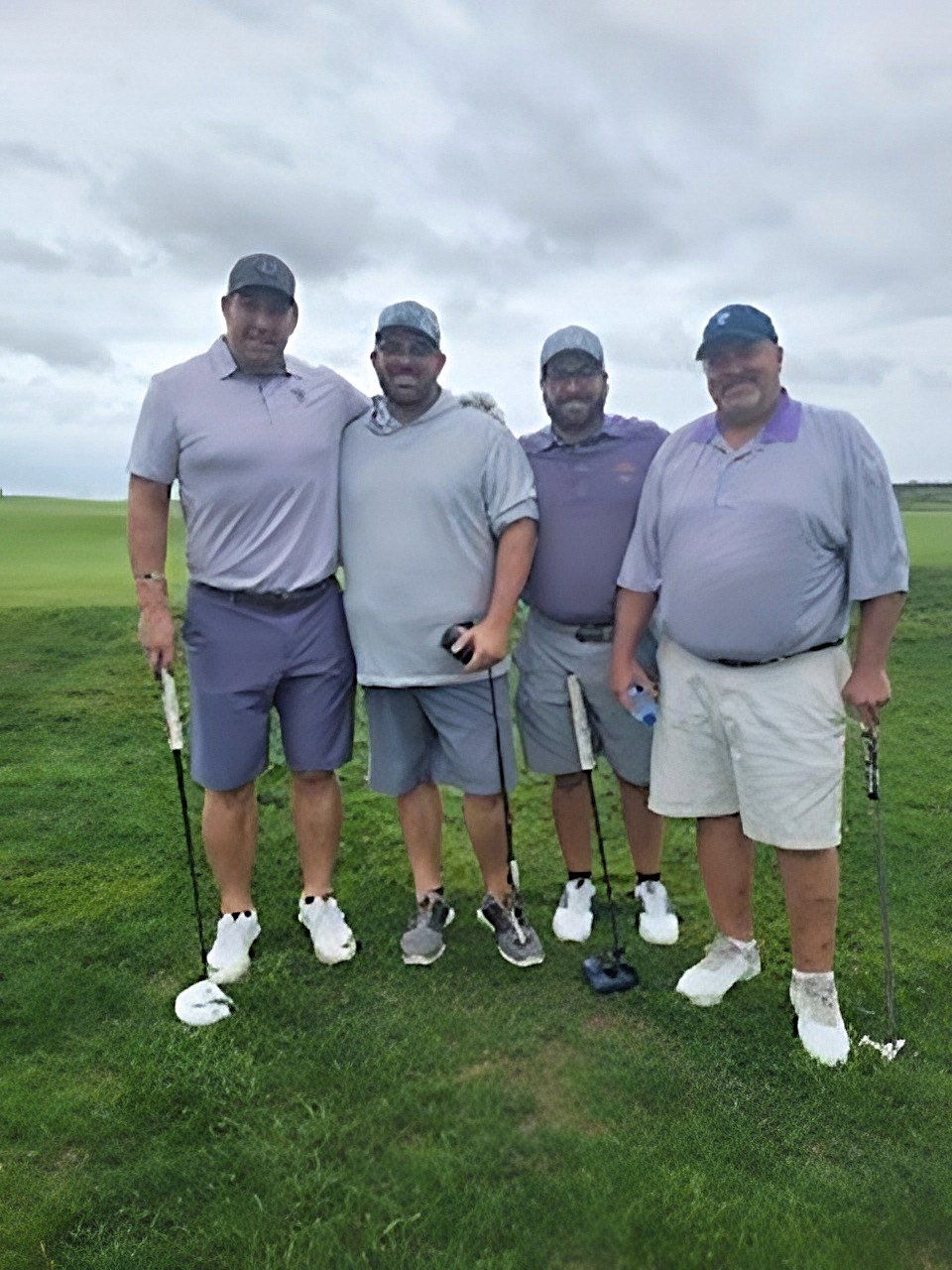 a group of men are posing for a picture on a golf course .