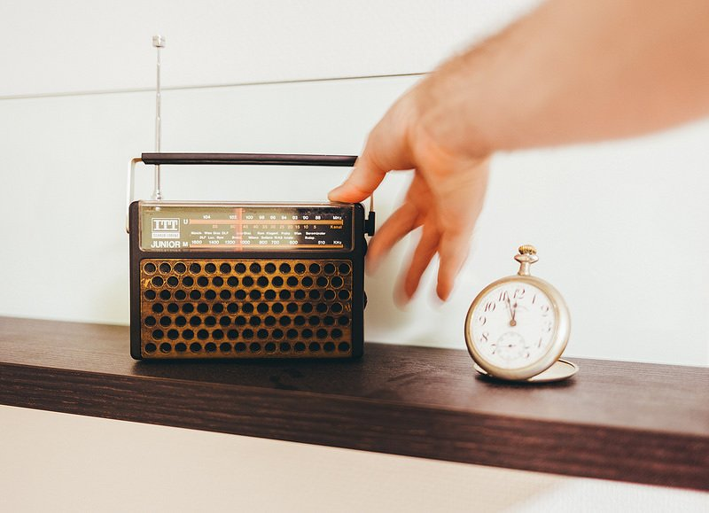 a hand is reaching for a radio next to a pocket watch