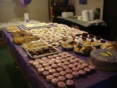 a table full of cupcakes and cakes with a purple table cloth