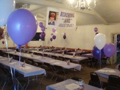 a room decorated with purple balloons and a sign that says remembering jane