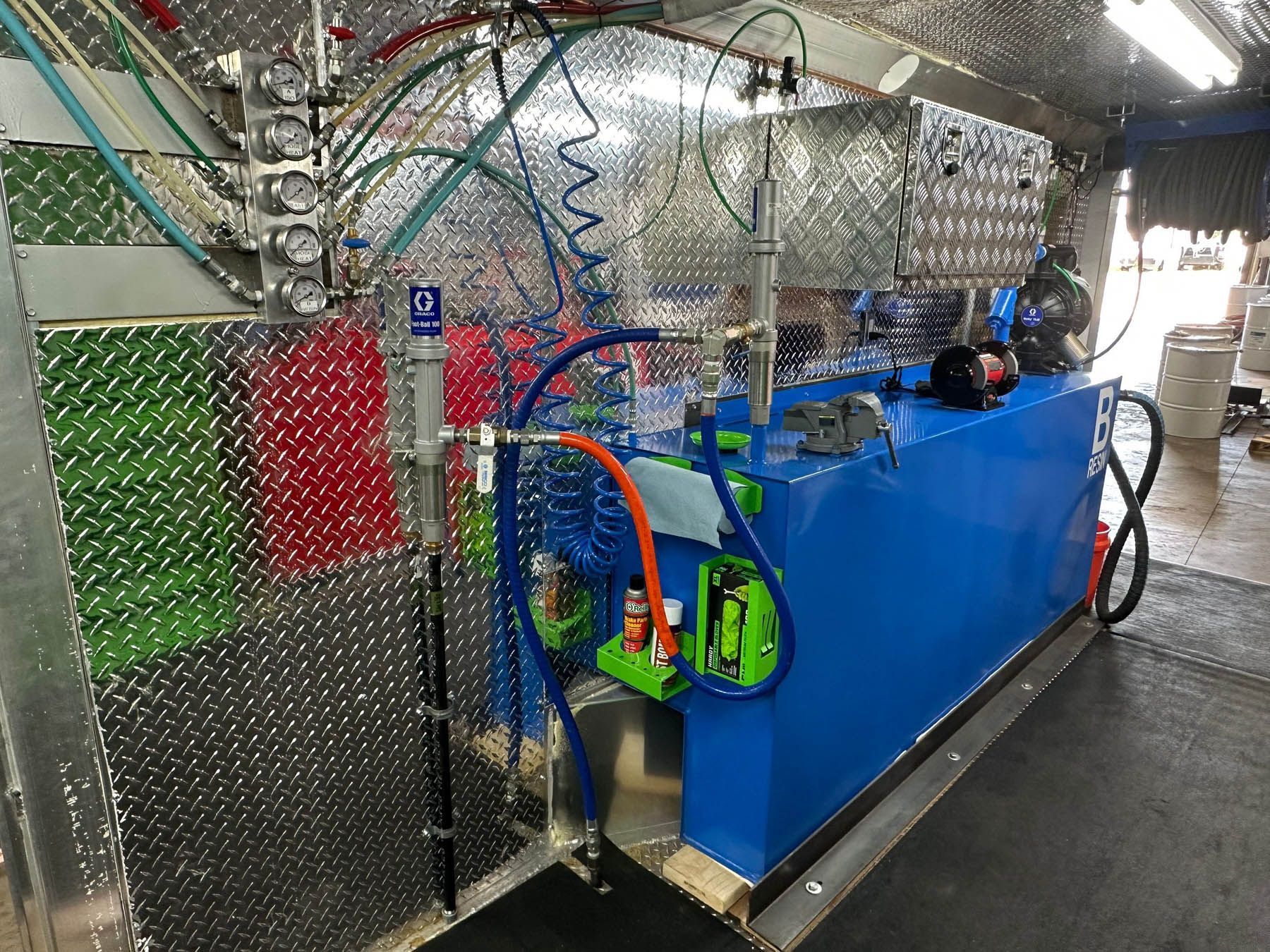 Blue tank and piping inside a trailer, with gauges and diamond plate walls.