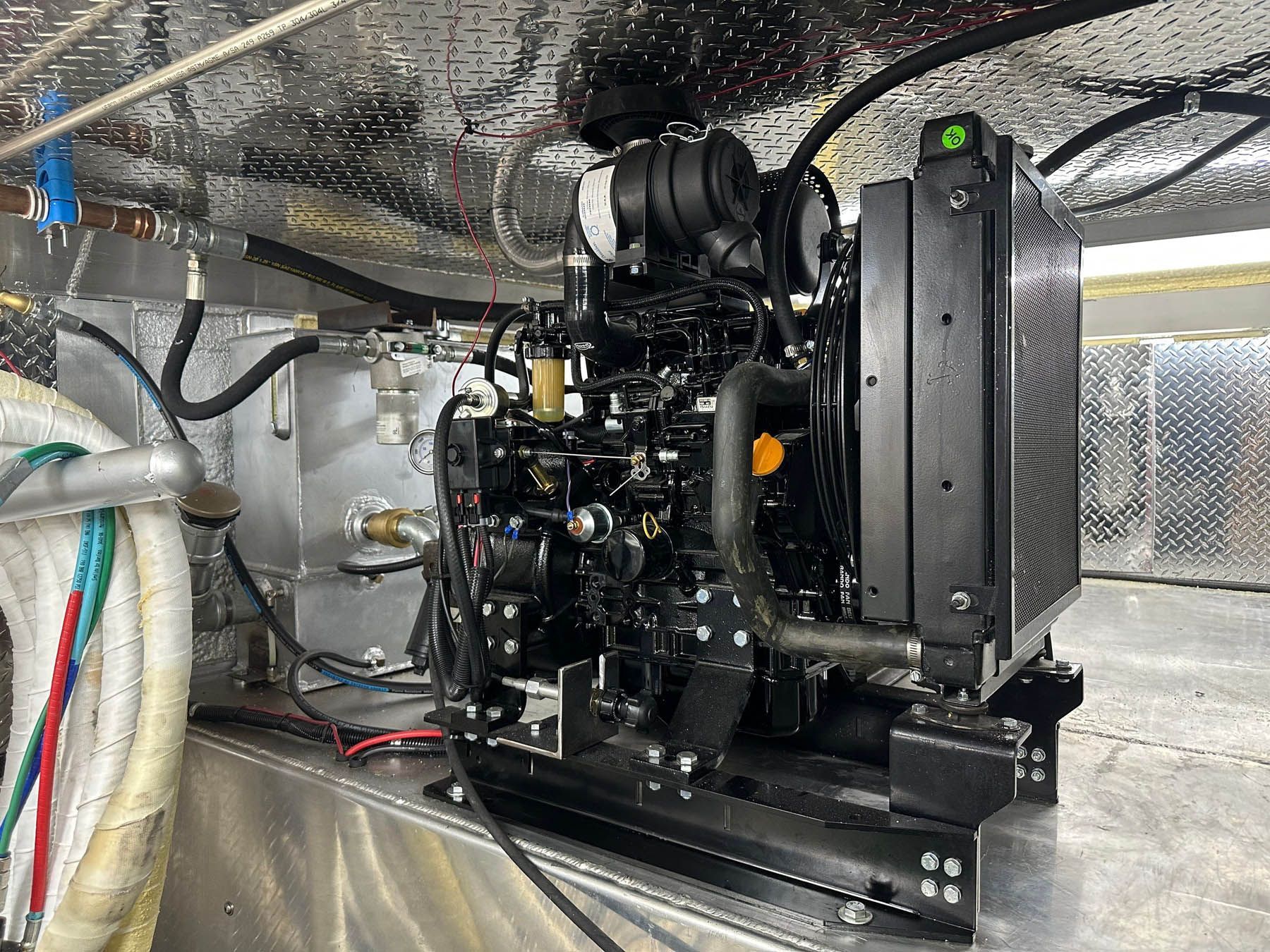 Diesel generator, black engine with radiator, mounted in a compartment.