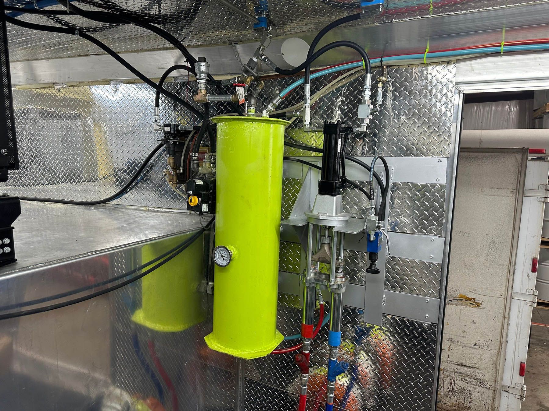 Yellow tanks and tubing inside a metallic enclosure, industrial setting.