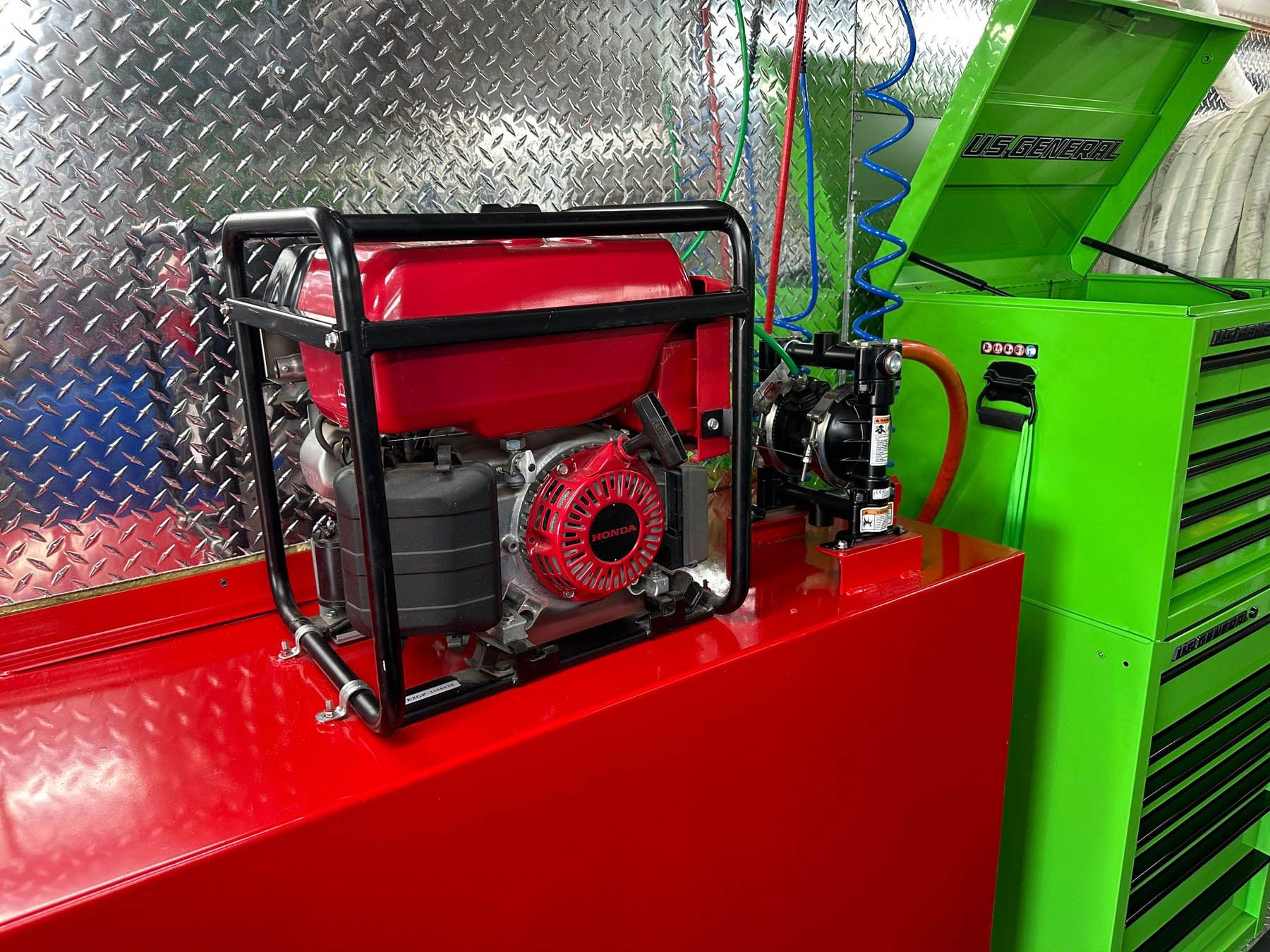 Red and black generator on a red box inside a metal walled space, with a green cabinet nearby.