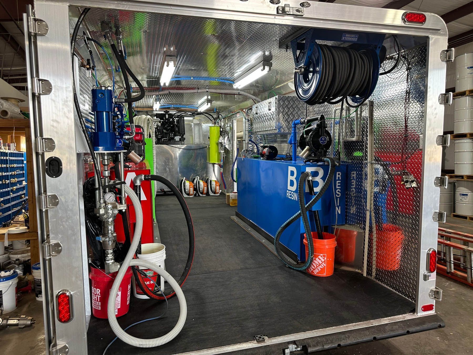 Interior of a service truck, tools and equipment, diamond plate walls, blue tank, hose reels, buckets.