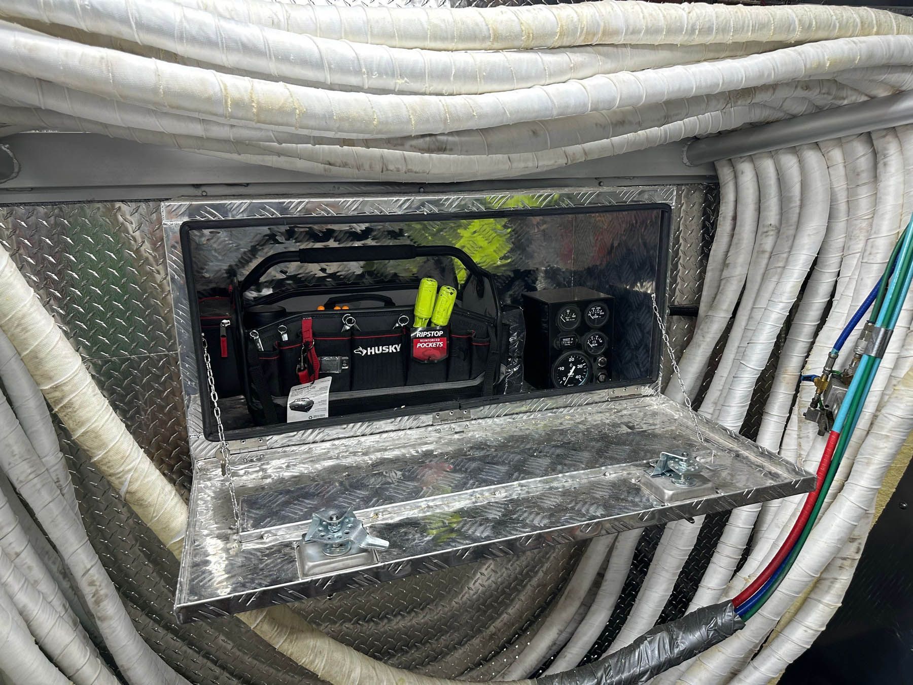 Metal toolbox with open door, containing a generator and other electrical components, surrounded by white electrical cables.