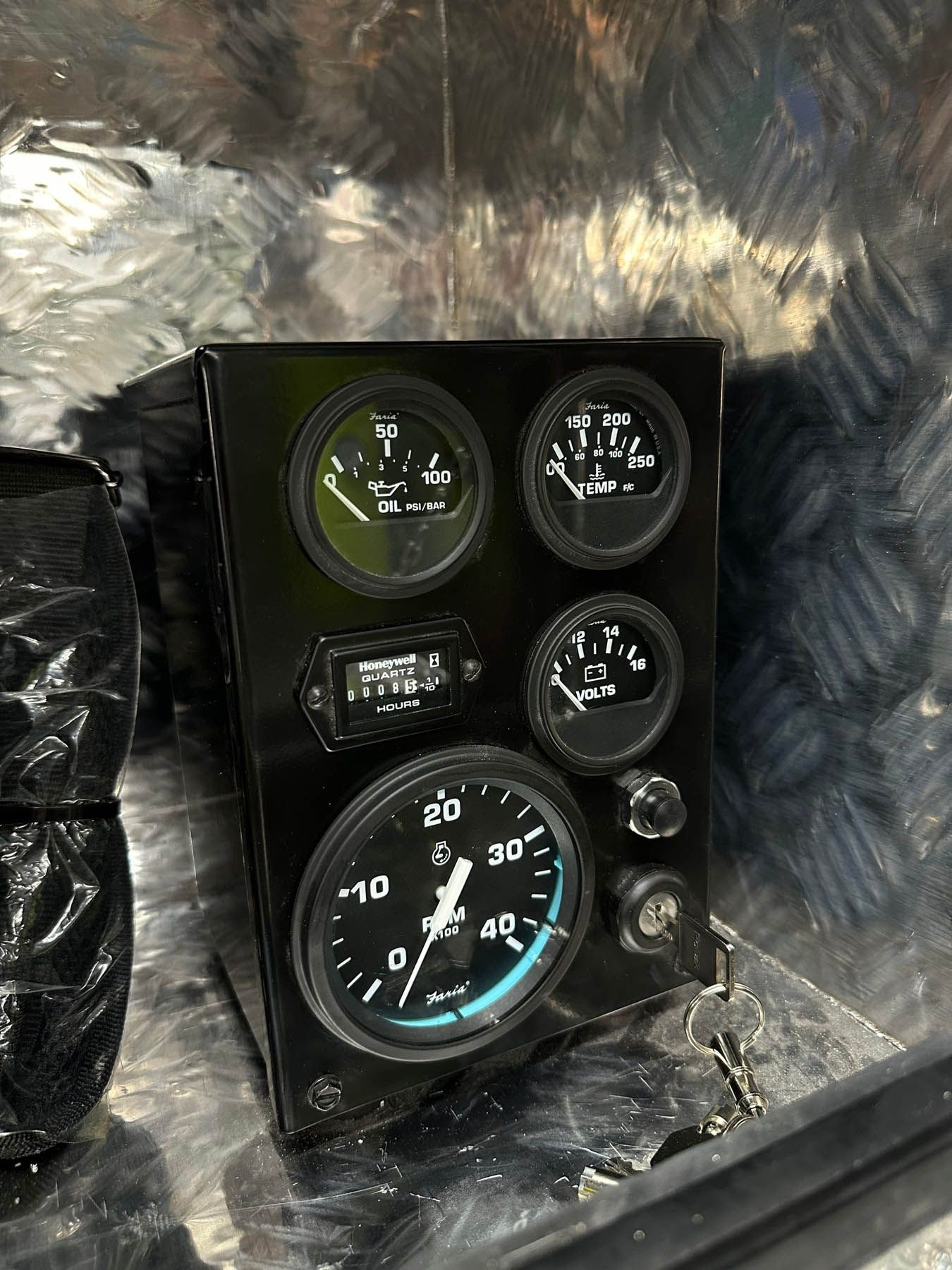 Black gauge panel with five round dials and a digital display, key and black surrounding structure.