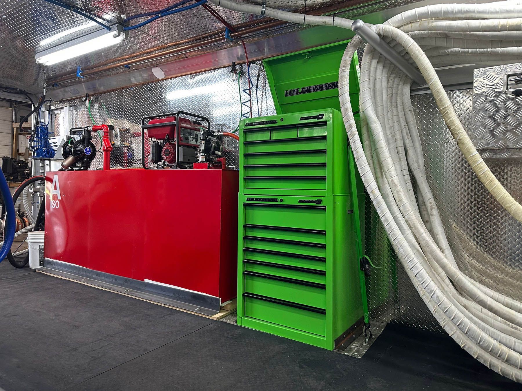 Inside a vehicle: Red fuel tank, green toolbox, hose, and equipment.
