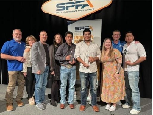 Group of people with awards under SPFA banner. Men in jeans and casual shirts, women in dresses and jackets.
