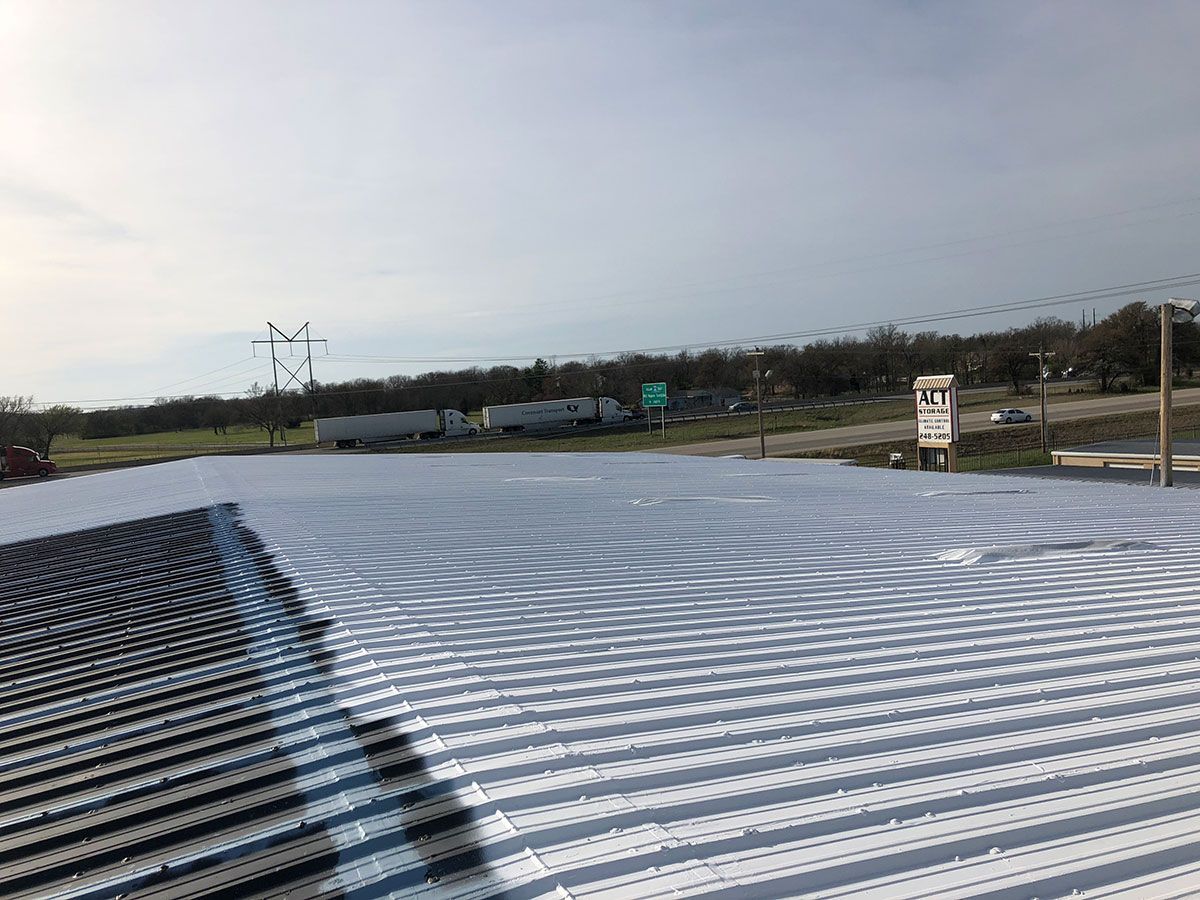Large, empty parking lot with repetitive pattern, trees, utility poles, and cloudy sky.