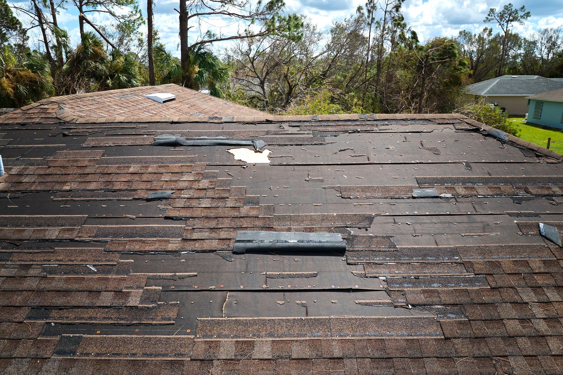 Aerial view of a building roof, partially painted white and gray. Parked vehicles surround the building.