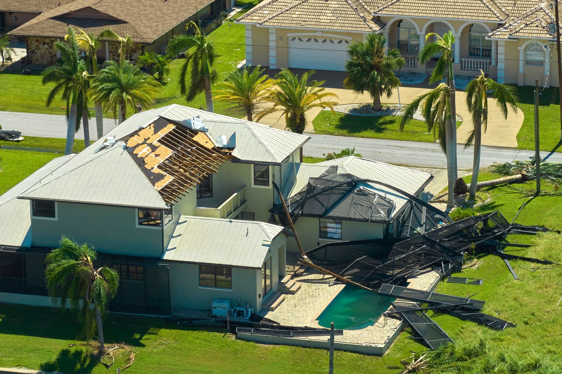 Aerial view of a building with a white flat roof and two brown pitched-roof sections, situated on a paved lot.