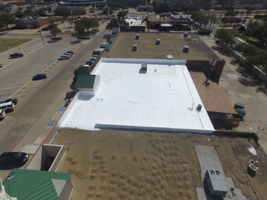 Aerial view of a commercial building with a newly installed white flat roof.