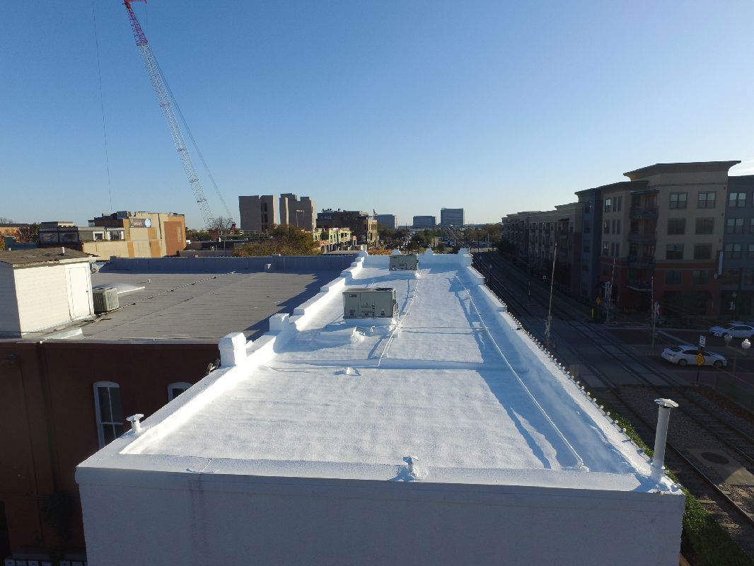 White flat roof overlooking a city street with buildings under a blue sky.