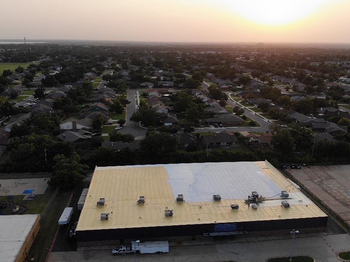 Aerial view of a warehouse roof under construction at sunset.