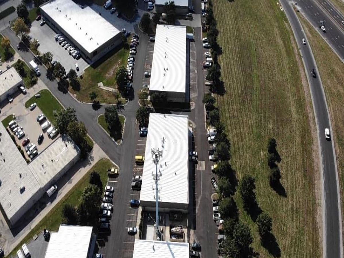 Aerial view of commercial buildings, parking lots, and a highway next to a grassy area.